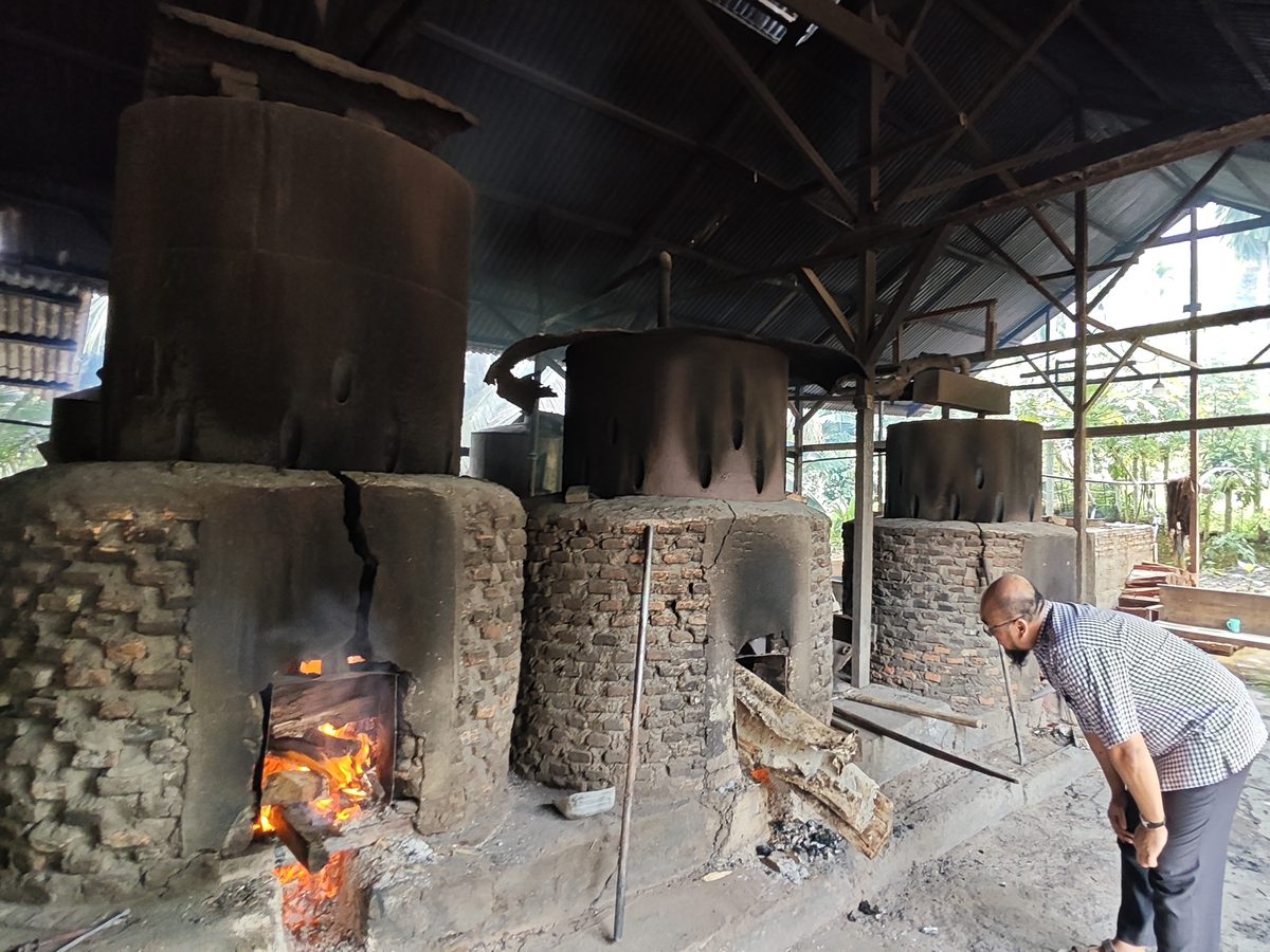 Three brick furnaces with steel vessels on top, one with a wood fire burning